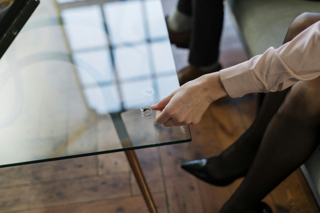 Close-up of a woman placing a wedding ring on a glass table, symbolizing relationship changes.